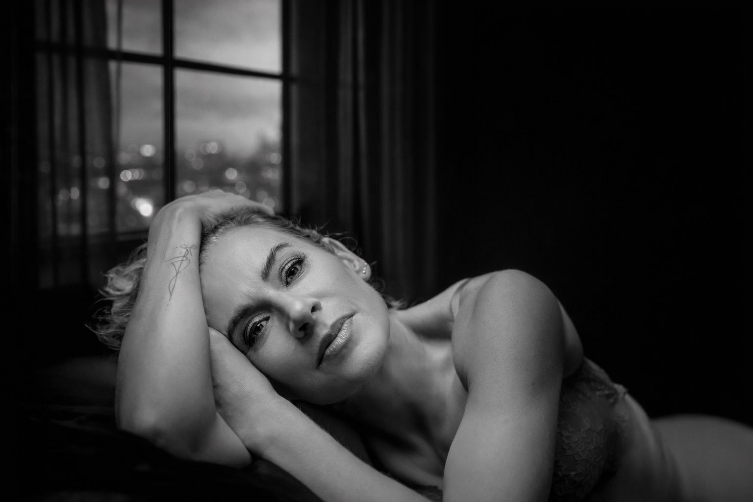 Zwart-wit boudoir fotoshoot portret van een vrouw liggend op sofa bij Studio Damon Wassenaar